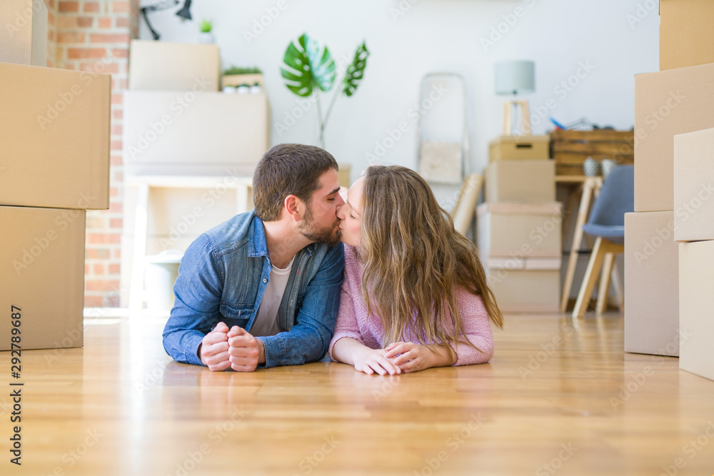 Young beautiful couple in love relaxing lying on the floor together with cardboard boxes around for moving to a new house Young beautiful couple in love relaxing lying on the floor together with cardboard boxes around for moving to a new house