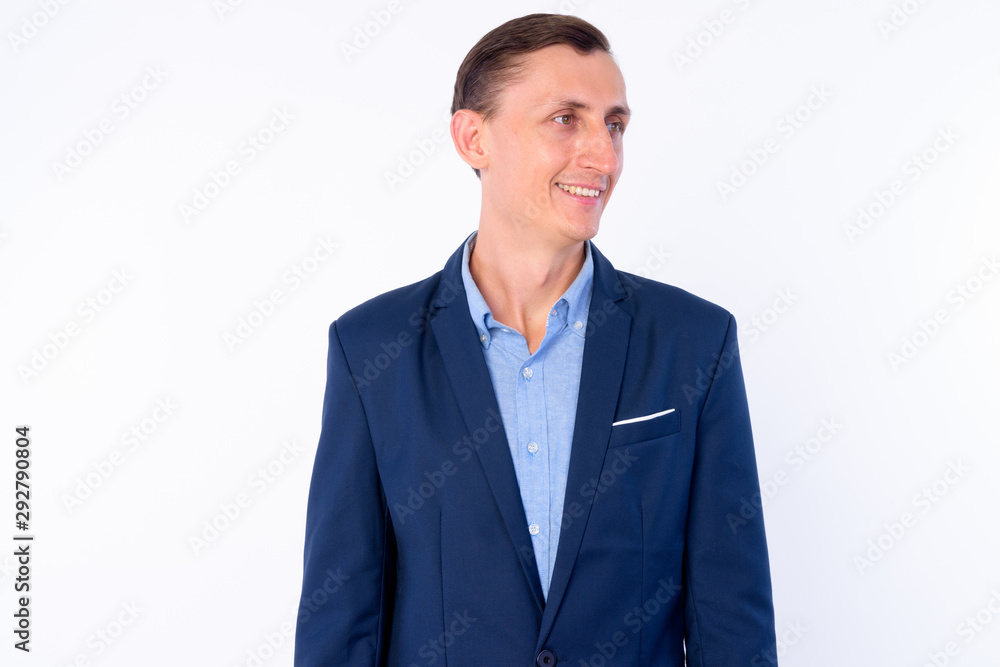 Studio shot of happy businessman in suit thinking and looking away