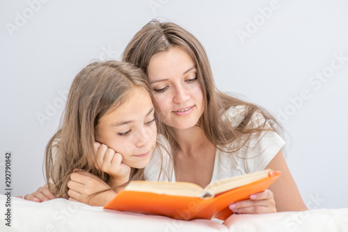 Young woman and her little  daughter reads the book before bedtime