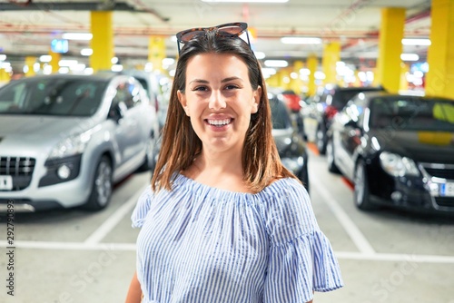 Young woman smiling confident at underground parking lot around cars and lights