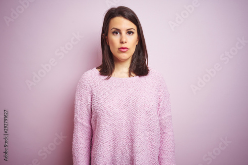 Young beautiful brunette woman wearing a sweater over pink isolated background Relaxed with serious expression on face. Simple and natural looking at the camera. © Krakenimages.com
