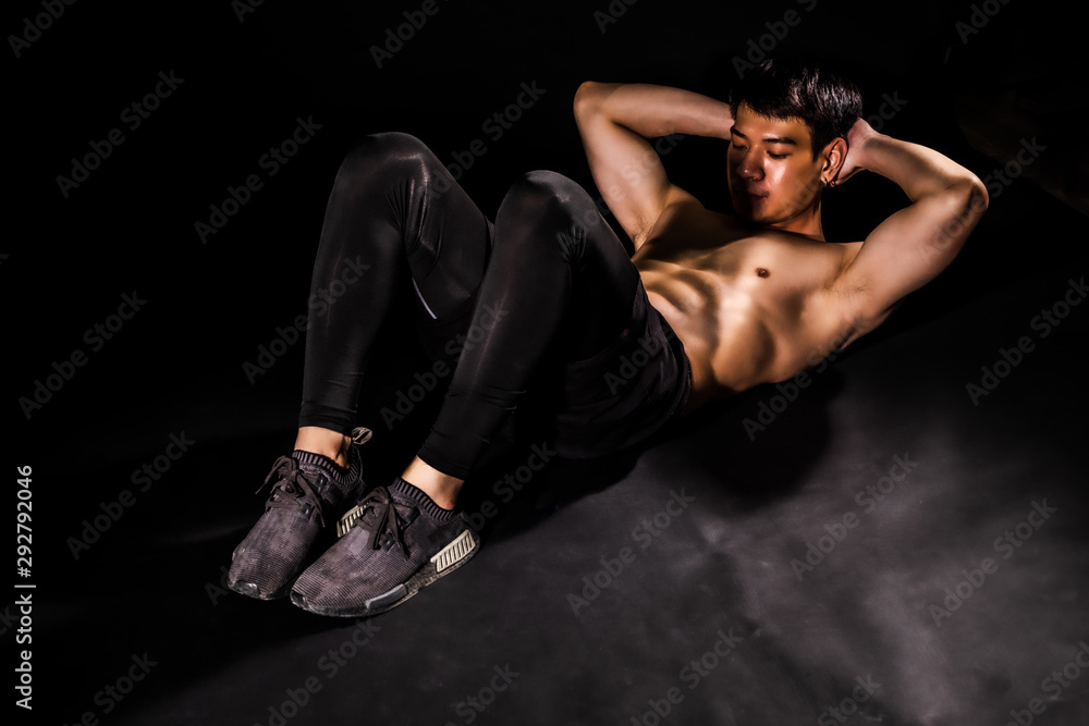 sport man at fitness gym club doing sit up exercise for body and showing muscle bodybuilding on black backgrounds, fitness concept, sport concept