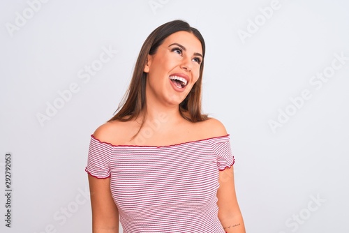 Portrait of beautiful young woman standing over isolated white background looking away to side with smile on face, natural expression. Laughing confident.