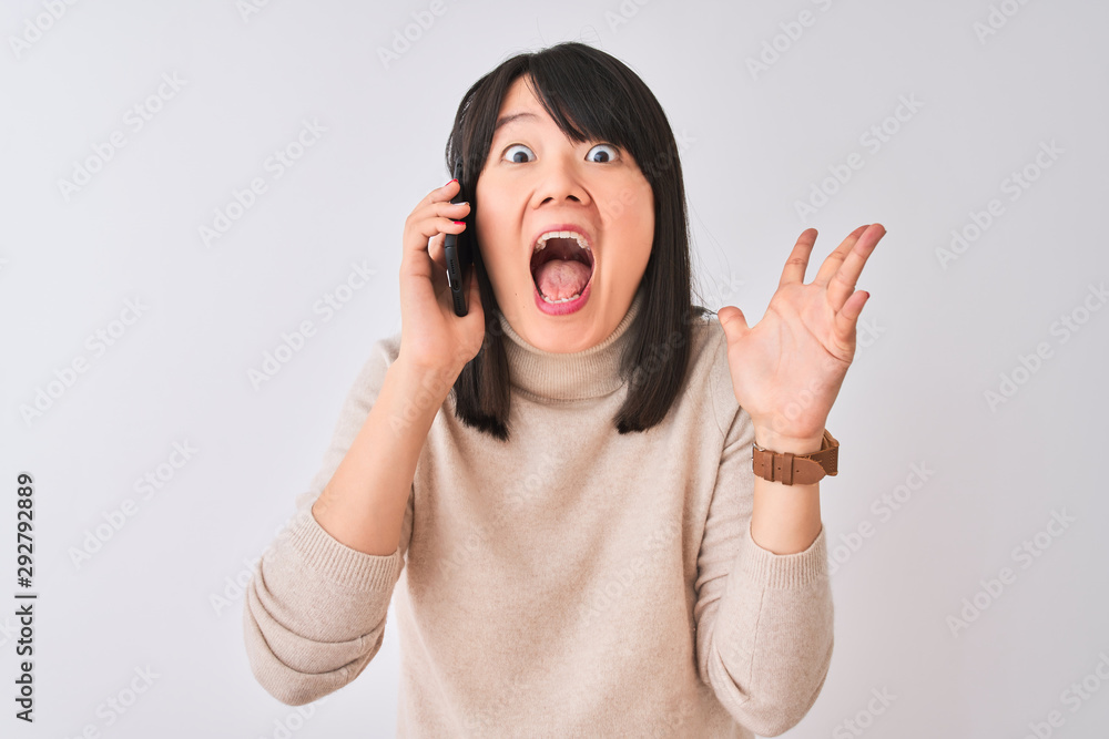 Young beautiful Chinese woman talking on the smartphone over isolated white background very happy and excited, winner expression celebrating victory screaming with big smile and raised hands Young beautiful Chinese woman talking on the smartphone over isolated white background very happy and excited, winner expression celebrating victory screaming with big smile and raised hands