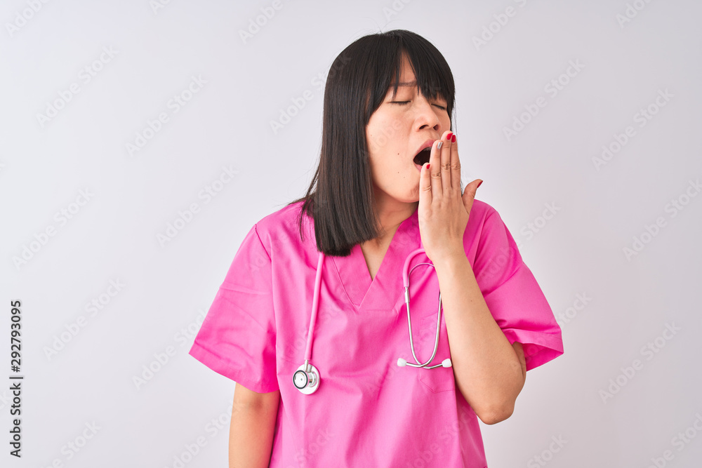 Young beautiful Chinese nurse woman wearing stethoscope over isolated white background bored yawning tired covering mouth with hand. Restless and sleepiness. Young beautiful Chinese nurse woman wearing stethoscope over isolated white background bored yawning tired covering mouth with hand. Restless and sleepiness.