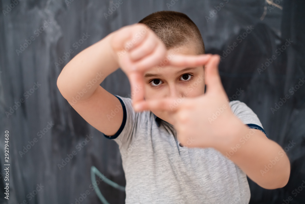 happy boy making hand frame gesture in front of chalkboard happy boy making hand frame gesture in front of chalkboard