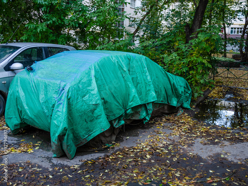 The car is covered with a cover for the winter.