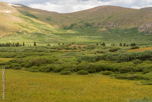 Alpine landscape of green meadow, mountain tops, and clouds at the top of Guanella Pass in Colorado