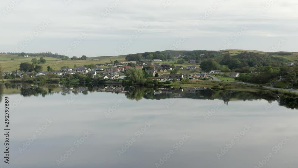 An aerial view of Lairg village reflected in the River Shin on a still summer's morning. Flying towards the village over the River Shin with zoom in. An aerial view of Lairg village reflected in the River Shin on a still summer's morning. Flying towards the village over the River Shin with zoom in.