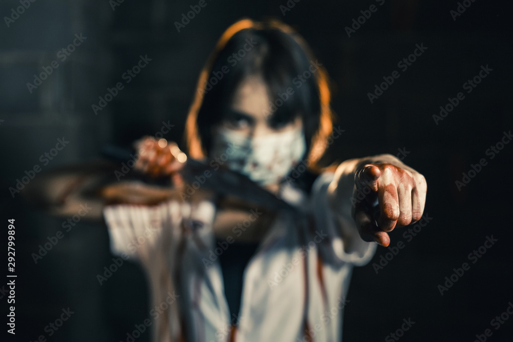 Nurse woman assassins with blood holding a knife in his hand in a dark room Point your finger forward, zombie horror lady. Halloween dressing concept.
