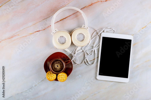 Overhead cup of black espresso coffee, tablet and headphone in marble background