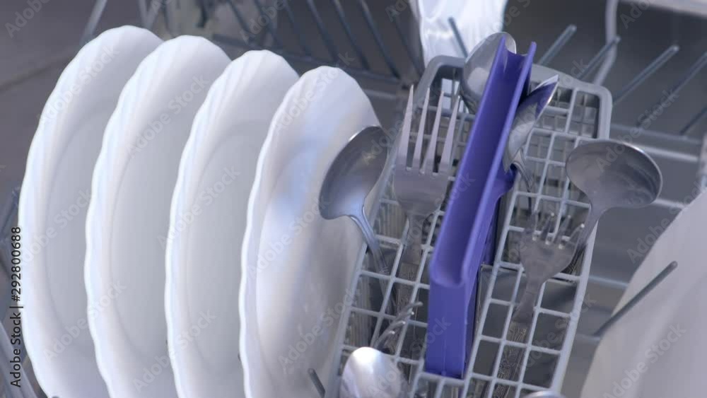 Man loading and unloading dishwasher white utensil and cutlery, high speed video. Washing dishes in kitchen, chores. Household duties using appliances in kitchen. Tableware and kitchenware. Man loading and unloading dishwasher white utensil and cutlery, high speed video. Washing dishes in kitchen, chores. Household duties using appliances in kitchen. Tableware and kitchenware.