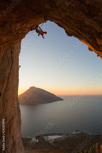 Silhouette of a climber in a cave above the Mediterranean sea with another island in view.. 