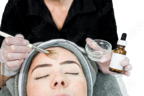 Close up of beautician (cosmetologist) applying chemical peel treatment on patient in a beauty spa, for skin rejuvenation, complexion and acne beauty treatments.