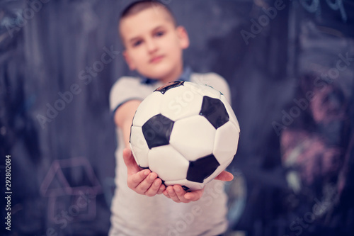 happy boy holding a soccer ball in front of chalkboard © .shock