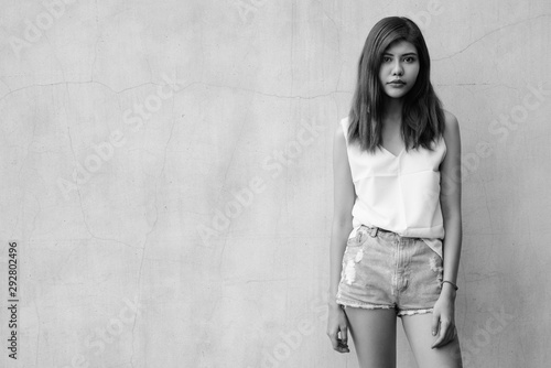 Beautiful teenager girl gray wall background outdoors shot in black and white