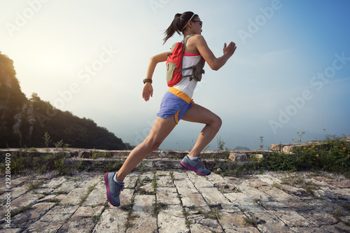 Fitness woman trail runner running at great wall on the top of mountain