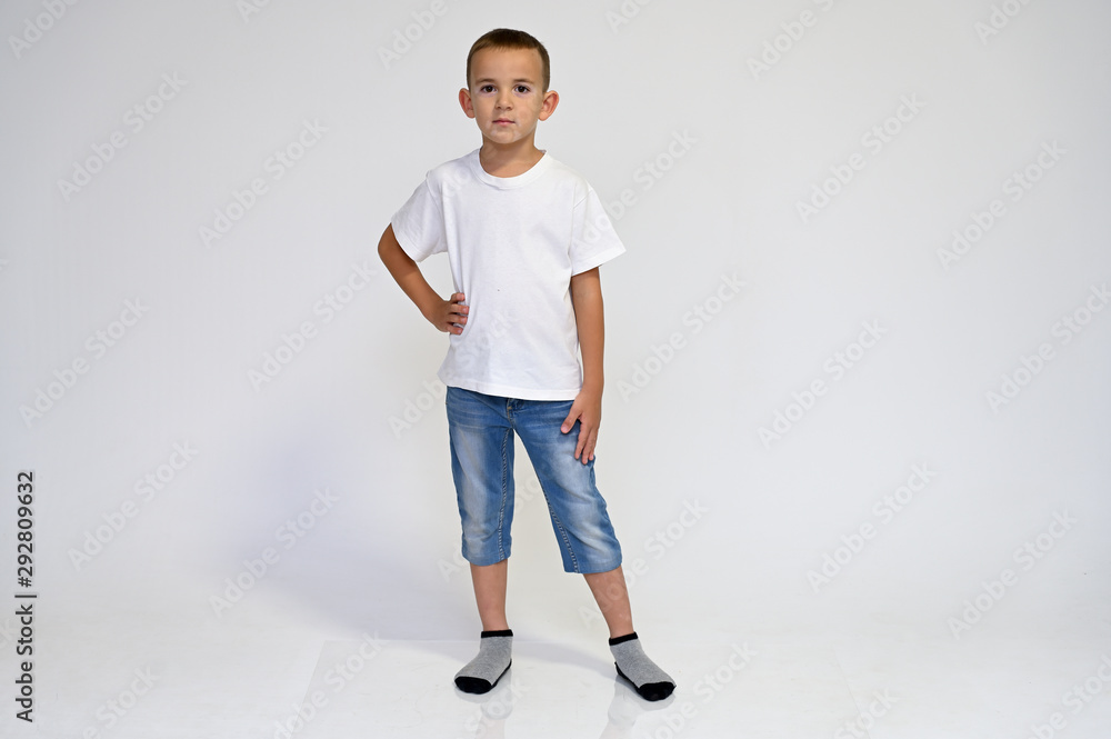 Full-length portrait on a white background of a cute boy child with Vitiligo disease - a violation of the color of the skin at the initial stage. White T-shirt, blue jeans. Full-length portrait on a white background of a cute boy child with Vitiligo disease - a violation of the color of the skin at the initial stage. White T-shirt, blue jeans.