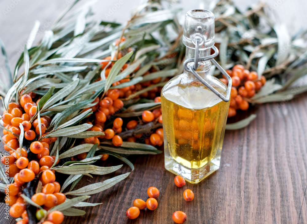 Leaves and berries of orange sea buckthorn on wooden table background Leaves and berries of orange sea buckthorn on wooden table background