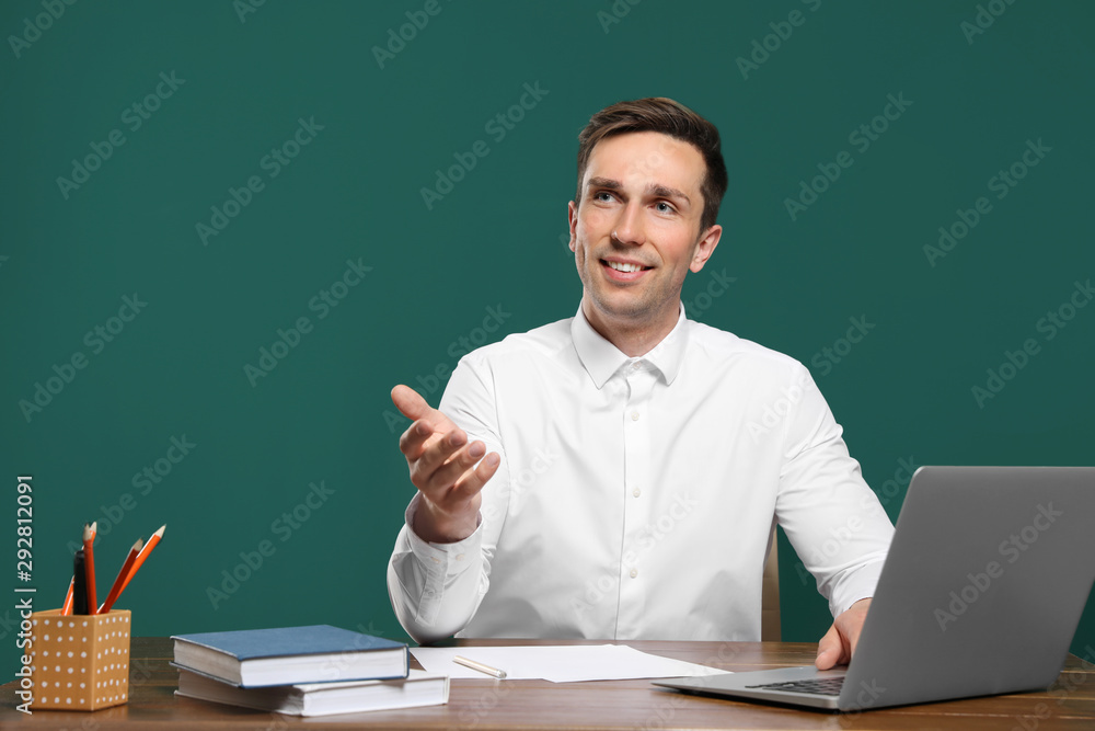 Portrait of male teacher working at table against color background Portrait of male teacher working at table against color background
