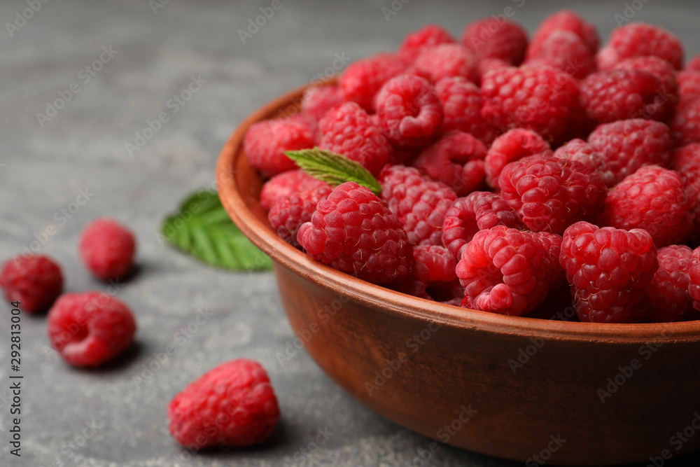 Bowl with delicious ripe raspberries on stone surface, closeup. Space for text Bowl with delicious ripe raspberries on stone surface, closeup. Space for text