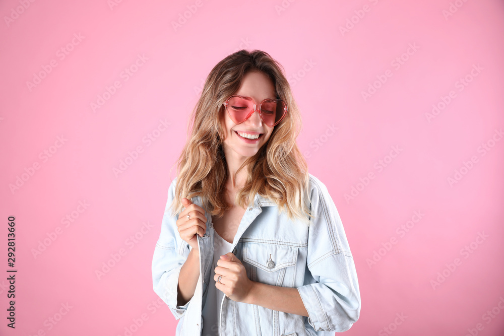 Young beautiful woman wearing heart shaped glasses on pink background