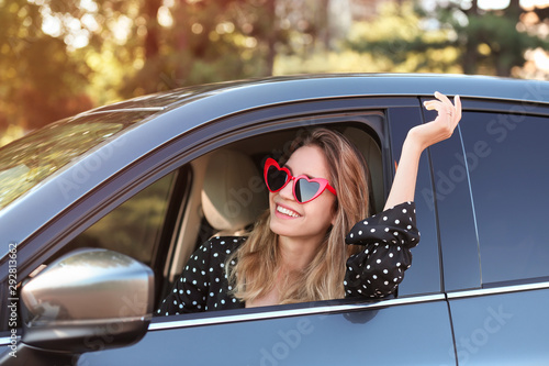 Young beautiful woman wearing heart shaped glasses in car photo