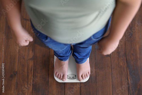 Fotografie Overweight boy standing on floor scales indoors, above view