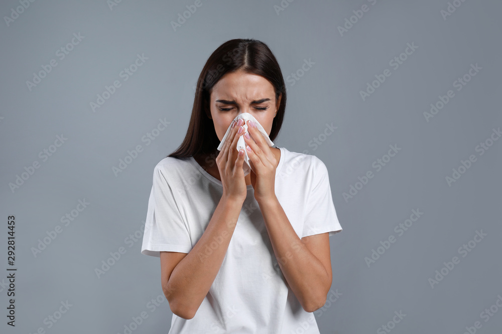 Young woman suffering from allergy on grey background Young woman suffering from allergy on grey background