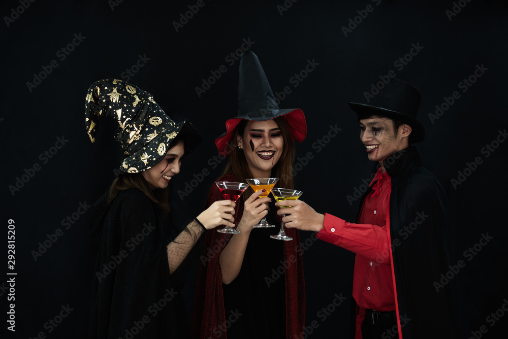 Three Asian people model dressed as Dracula and witch and a witch's hat costume smile and acting on Halloween party standing with a dark background.