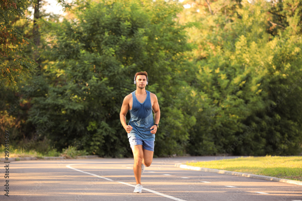 Young man with headphones running in park Young man with headphones running in park