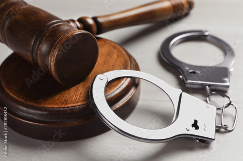 Judge's gavel and handcuffs on white wooden background, closeup. Criminal law concept photo