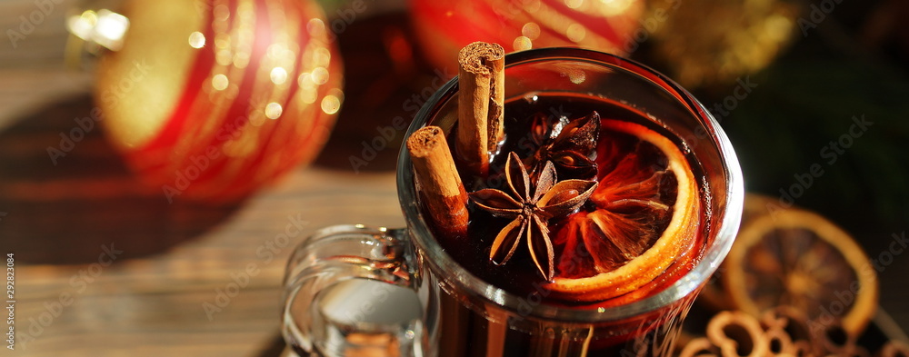 Christmas mulled vine with spices sinnamon stiks, anice stars, orange and New Year decorations on a wooden rustik table. Banner. Selective focus. Traditional hot drink at Xmas holiday - obrazy, fototapety, plakaty 