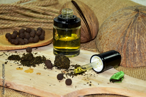 Hemp oil in a clear bottle and a dropper with yellow marijuana leaves dry ground. Placed on a wooden cutting board