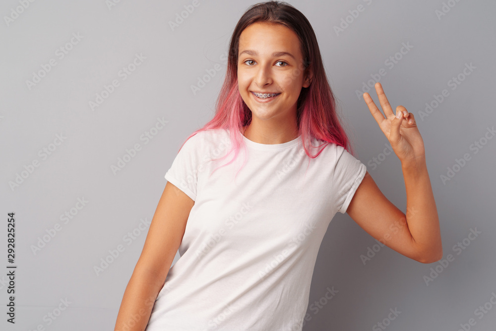 Happy young teen girl winner celebrating success over gray background Happy young teen girl winner celebrating success over gray background