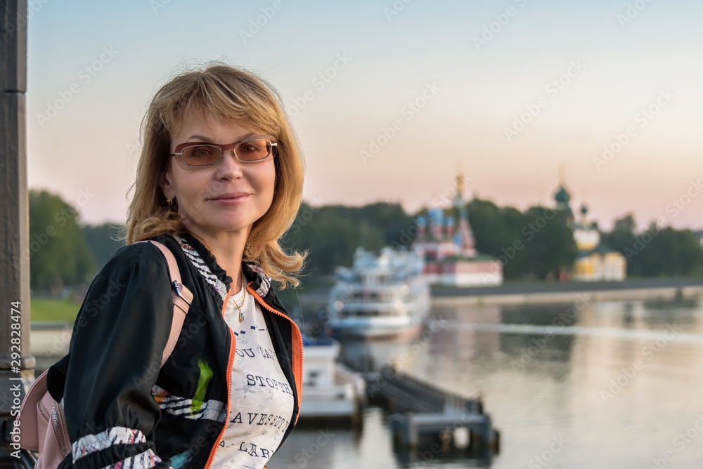 Fototapeta premium Portrait of an attractive woman against the background of the ancient city and the ships standing at the pier.