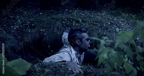 Zombie climbs out of the grave in the night cemetery. Halloween. Horror.