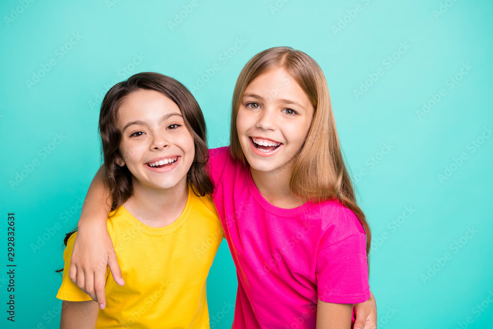 Photo of two friendly kind amazing beautiful girls being glad to be photographed while isolated with teal background Photo of two friendly kind amazing beautiful girls being glad to be photographed while isolated with teal background