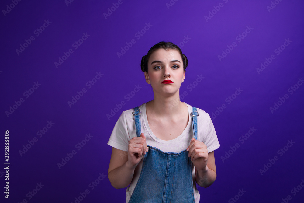 Portrait of girl wearing denim overalls and pink t-shirt on purple background Portrait of girl wearing denim overalls and pink t-shirt on purple background
