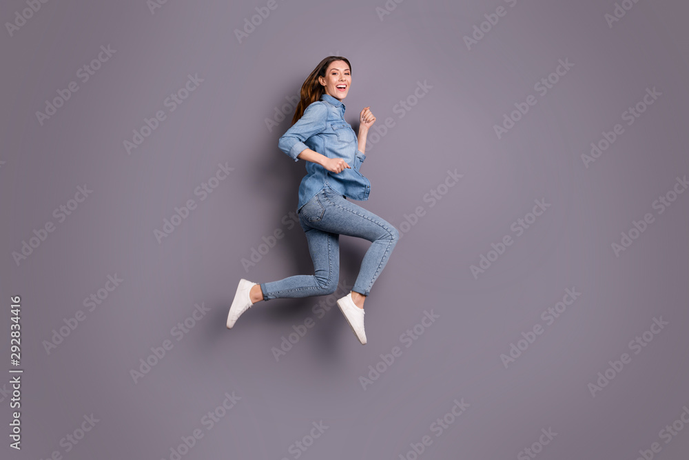 Full length profile photo of pretty lady jumping high running to attend sale in shopping center wear casual jeans outfit isolated grey background - obrazy, fototapety, plakaty 