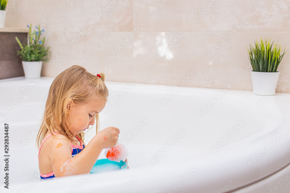 Funny little blonde girl taking bubble bath in beautiful bathroom.Kids hygiene. Shampoo, hair treatment and soap for children. Copyspace. Funny little blonde girl taking bubble bath in beautiful bathroom.Kids hygiene. Shampoo, hair treatment and soap for children. Copyspace.
