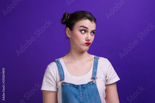 Portrait of girl thinks about something against purple background