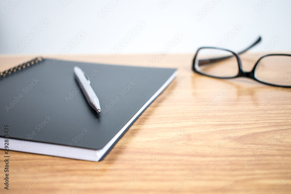 Close up, business desk side view with notebook, pen and eyeglasses. Close up, business desk side view with notebook, pen and eyeglasses.
