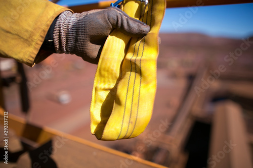 Rigger inspector high risk worker hand wearing heavy duty glove holding inspecting a yellow three lifting sling prior used in Sydney city construction building site, Australia 