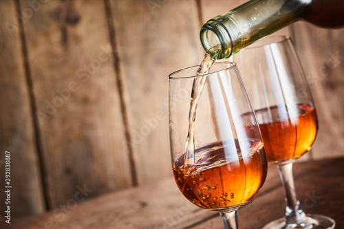 Fototapeta Rich golden sherry being poured into a wineglass