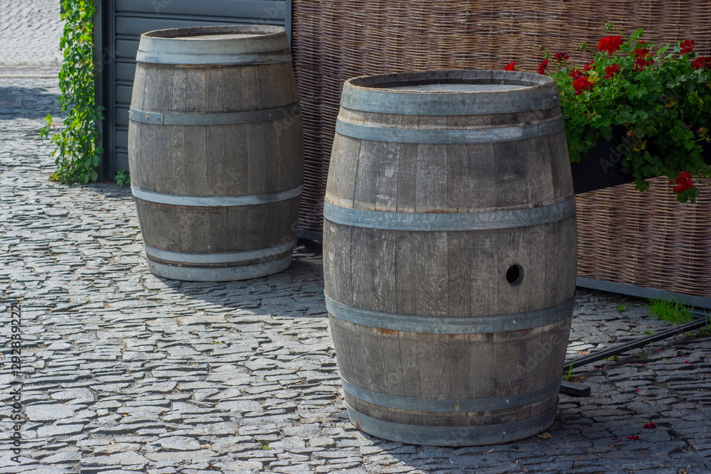 Empty wooden wine barrels with a hole for a tap or cork standing on the street. Empty wooden wine barrels with a hole for a tap or cork standing on the street.