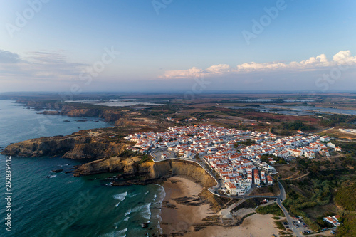 Aerial view of the Zambujeira do Mar village and beach at sunset, in Alentejo, Portugal;