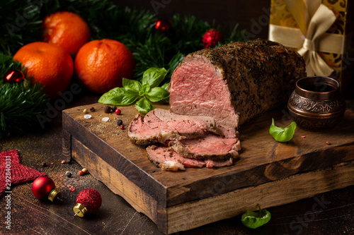 Juicy roast beef with spices sliced on cutting Board, delicious meat, traditional food. Christmas holidays, new year, menu on dark background