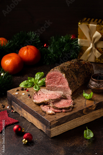 Juicy roast beef with spices sliced on cutting Board, delicious meat, traditional food. Christmas holidays, new year, menu on dark background