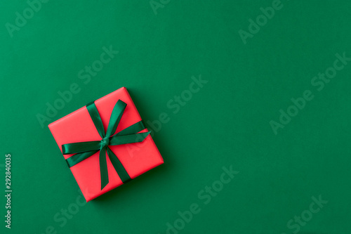 Red gift box on green background. Christmas card. Flat lay.Top view with space for text	